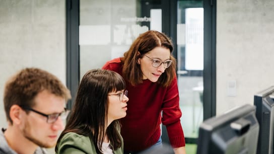 Un'insegnante aiuta una studentessa con il computer durante un seminario all'università.