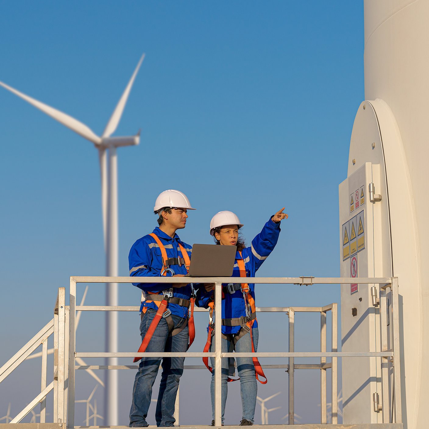 Maintenance engineers are checking wind turbines at wind power plant electric energy station