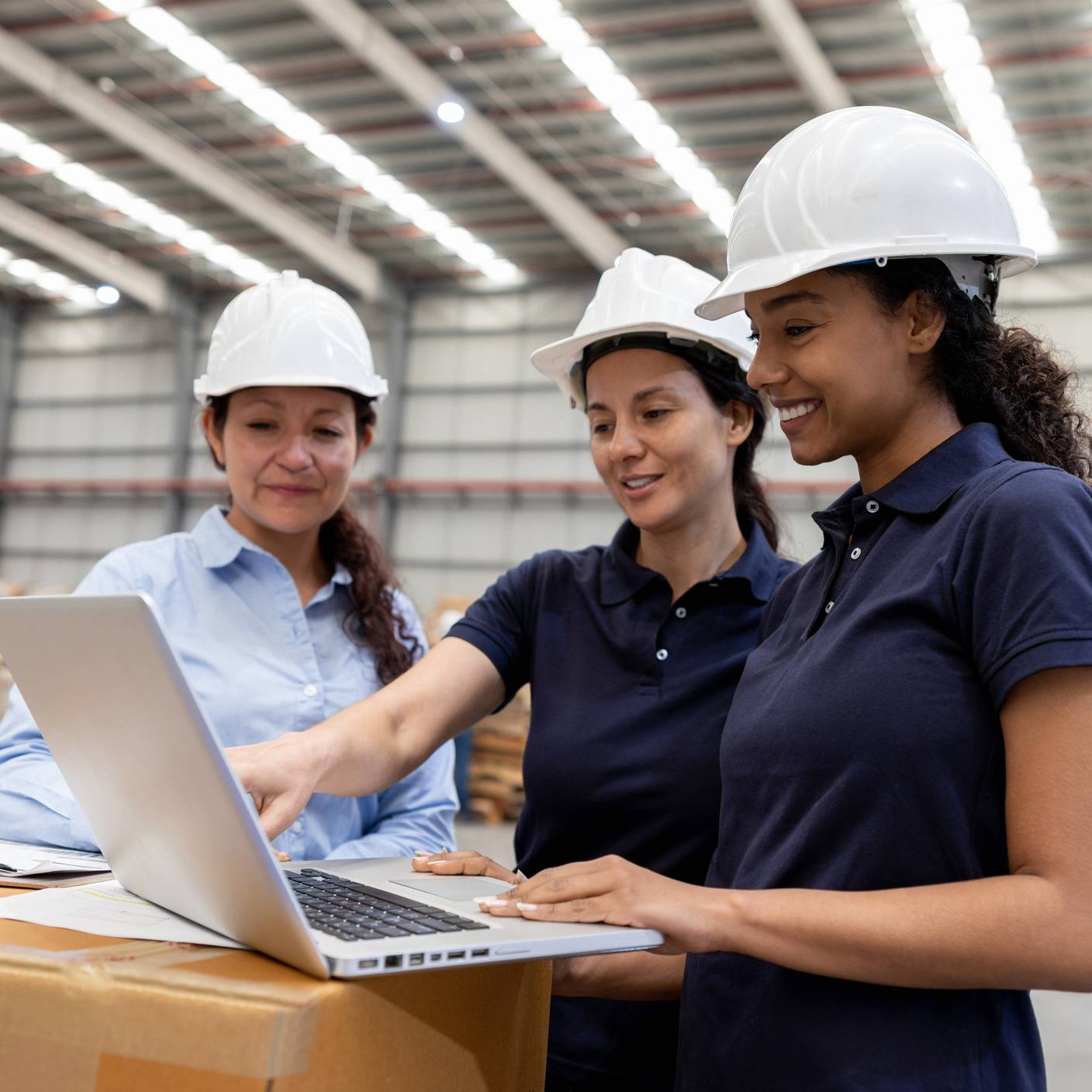 Equipo de mujeres que trabajan en un almacén de distribución coordinando la logística de envío con una computadora portátil.