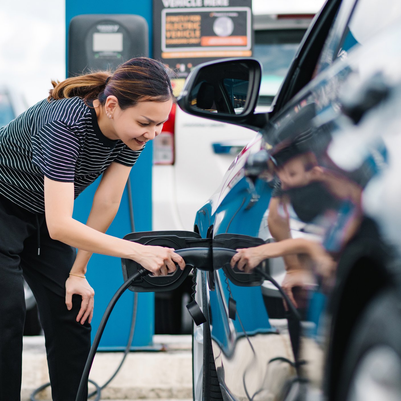 female charging her electric car.