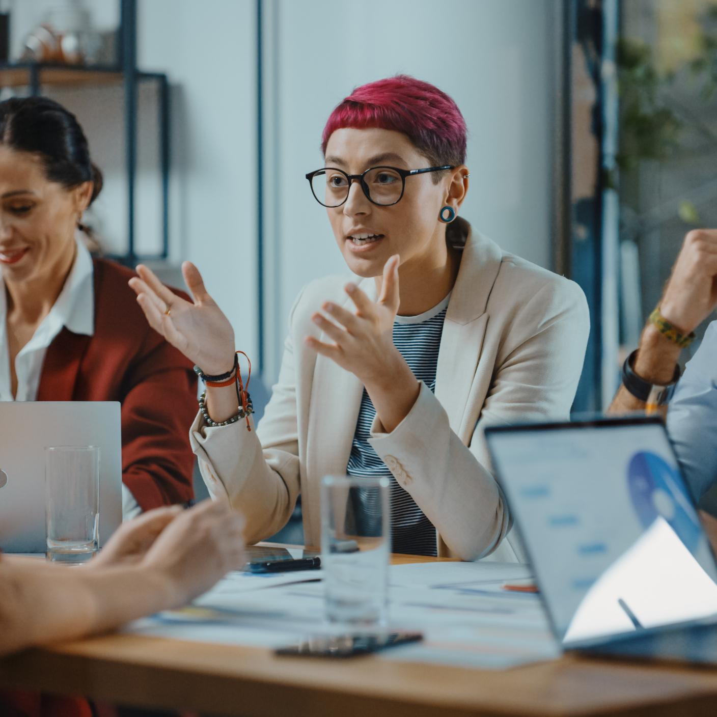 Office Meeting in Conference Room: Beautiful Specialist with Short Pink Hair Talks about Firm Strategy with Diverse Team of Professional Businesspeople. Creative Start-up Team Discusses Big Project