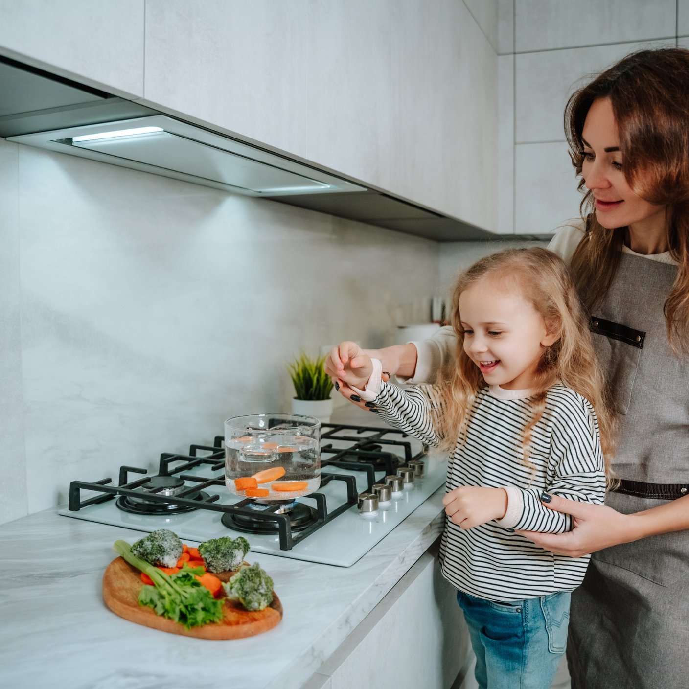 mum and daughter cooking on gas hob 