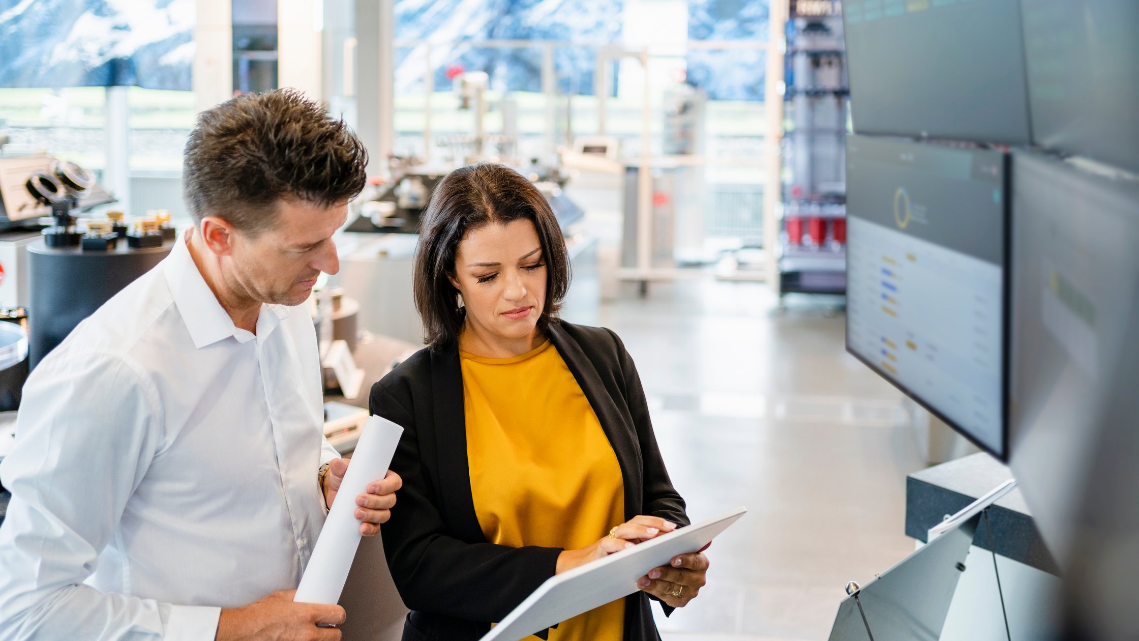 Businesswoman using tablet PC standing by colleague in industry